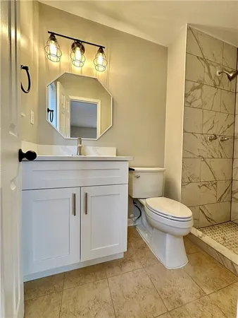a bathroom with a granite countertop toilet sink mirror and vanity