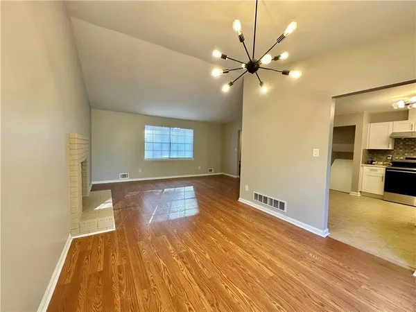a view of an empty room with window and wooden floor