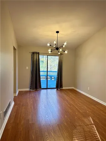 a view of an empty room with glass door and wooden floor