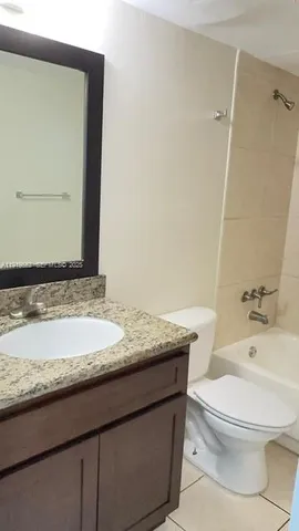 a bathroom with a granite countertop toilet sink and mirror