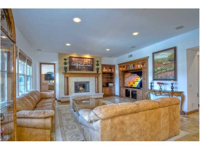 2461 Lapis Road Carlsbad, CA 92009 - Photo 10 of 25 Flowing from the kitchen is this warm family room creating that great room feel. A focal point is the custom fireplace mantle and stunning glass tiled backsplash.