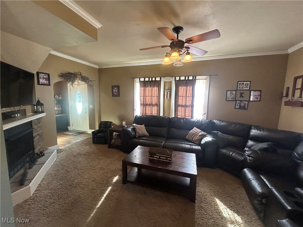 150 West Athens Road Roseville, OH 43777 - Photo 2 of 17 Living area with ornamental molding, carpet floors, arched walkways, a ceiling fan, and a fireplace