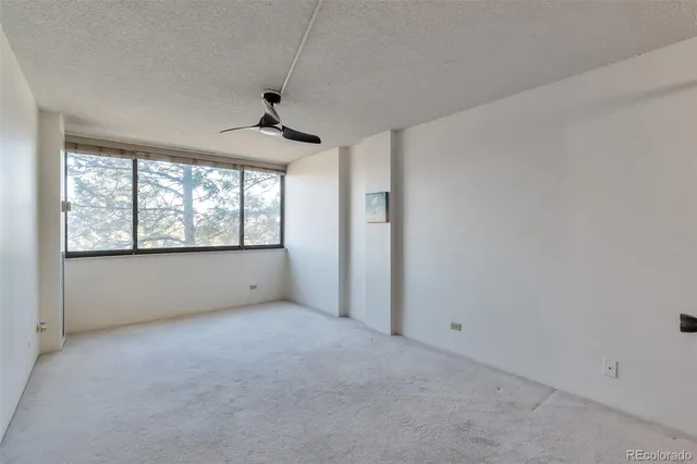 an empty room with windows and ceiling fan