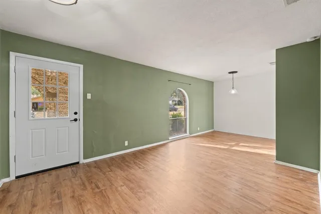 a view of a hallway with wooden floor and a kitchen