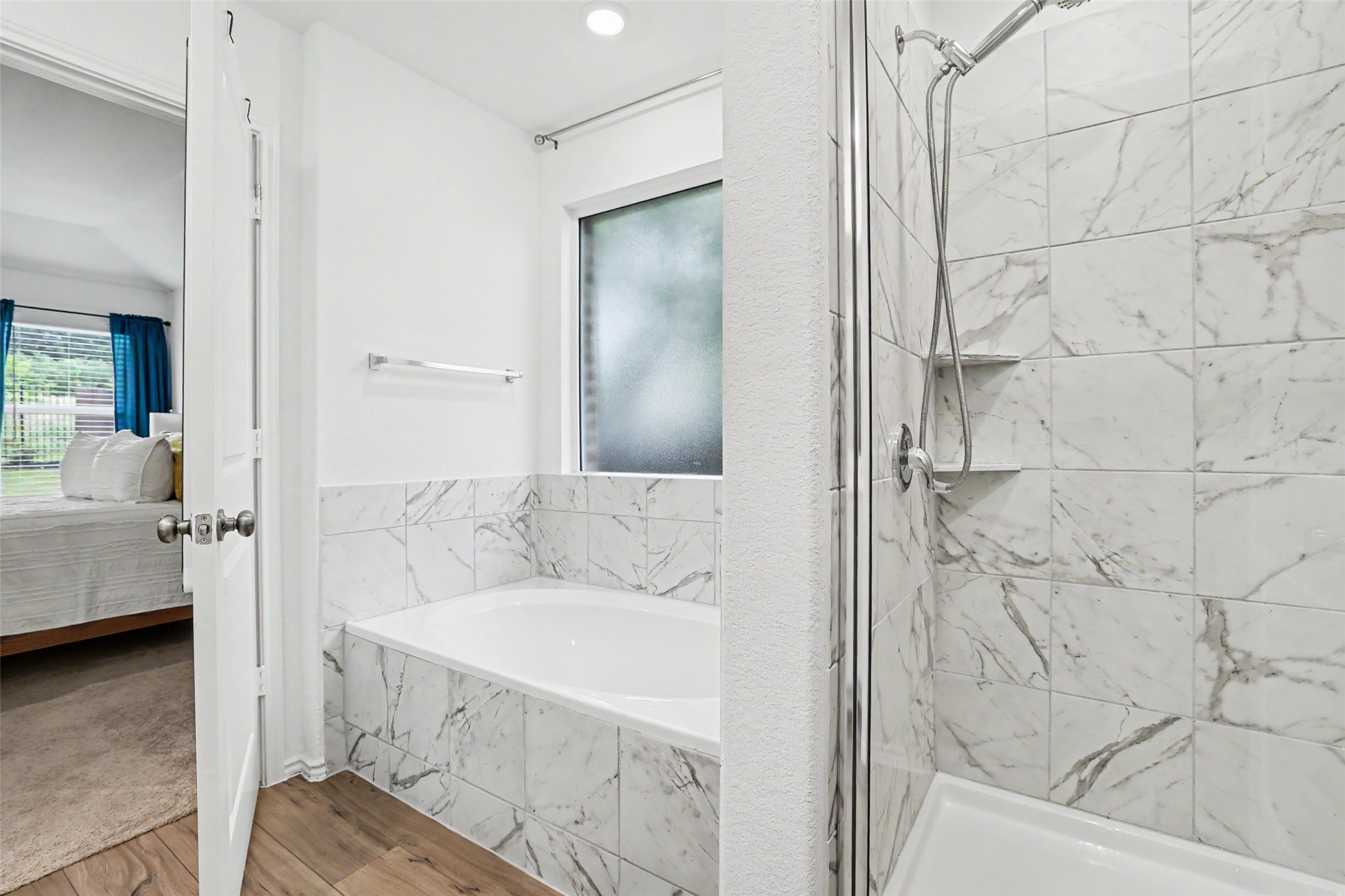2333 Four Waters Loop Georgetown, TX 78628 - Photo 23 of 35 Soaking tub with marble-look tile surround and wood-finish flooring