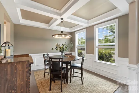 a dining room with wooden floor a chandelier a wooden table and chairs
