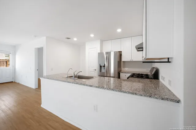 a kitchen with stainless steel appliances granite countertop a sink a refrigerator and a granite counter tops