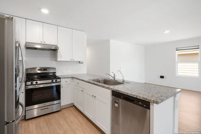 a kitchen with stainless steel appliances granite countertop a stove a sink and a refrigerator