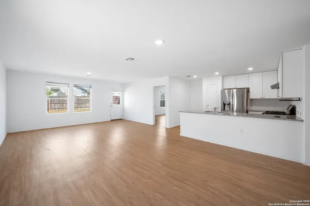 a view of an empty room with window and wooden floor