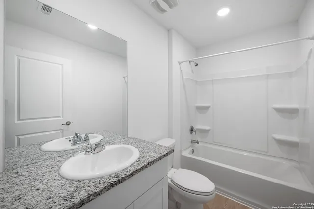 a bathroom with a granite countertop sink toilet tub and shower