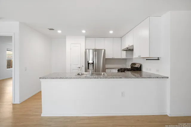 a view of kitchen with stainless steel appliances granite countertop refrigerator sink and stove