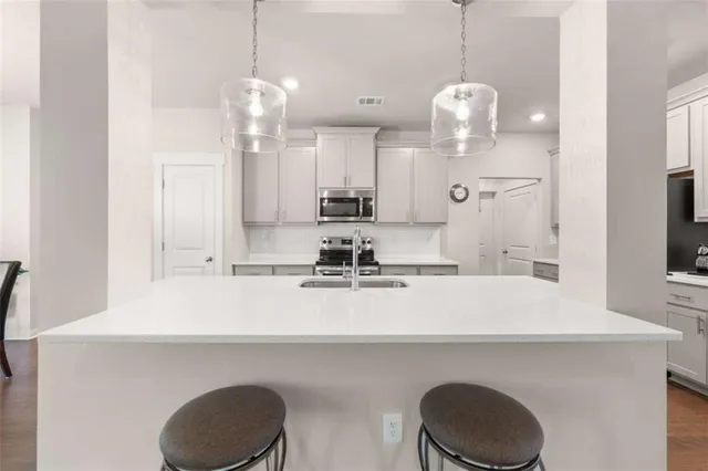 a kitchen with kitchen island granite countertop a sink a stove and a chandelier