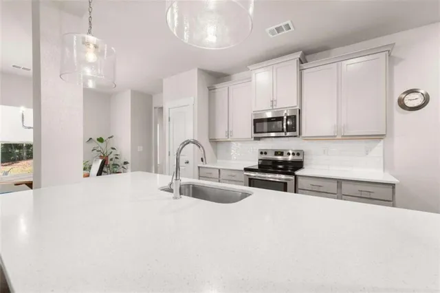 a kitchen with granite countertop a stove a sink a microwave and refrigerator