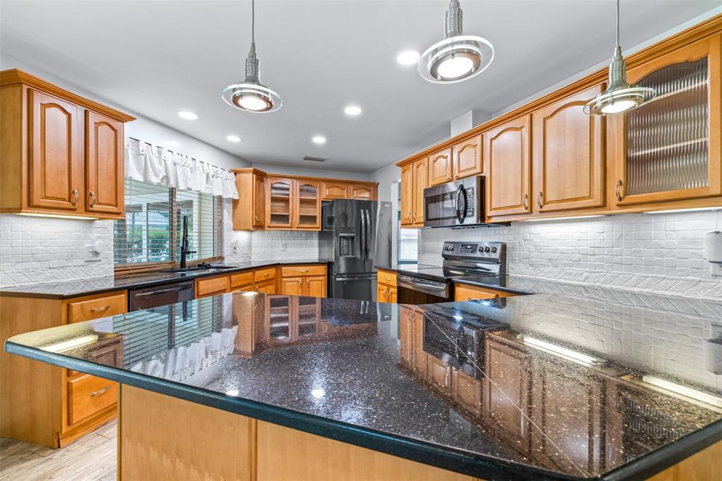 3404 Brian Road South Palm Harbor, FL 34685 - Photo 13 of 71 a kitchen with stainless steel appliances granite countertop a sink a stove and a wooden cabinets