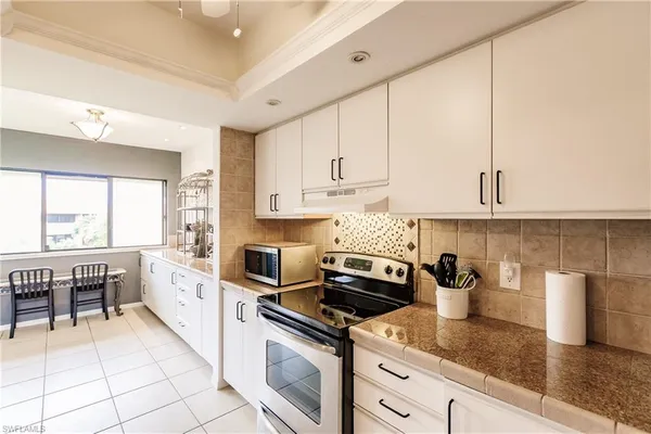 a kitchen with granite countertop a sink a stove and cabinets