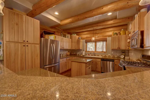 a kitchen with stainless steel appliances granite countertop a refrigerator a sink a stove and oven