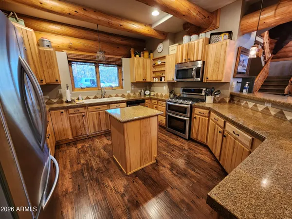 a kitchen with stainless steel appliances granite countertop wooden floors a stove top oven a sink and dishwasher