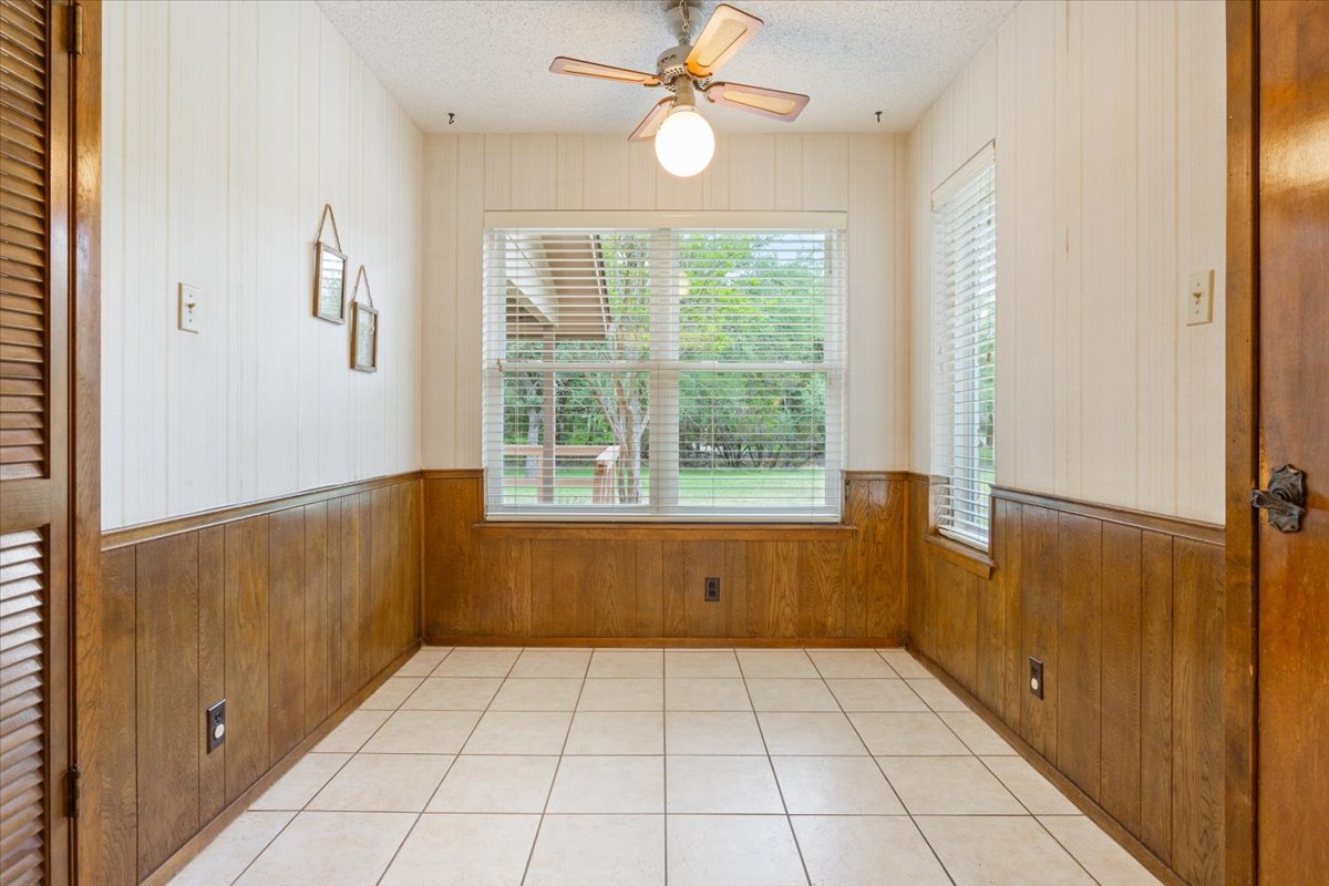 4015 Ramada Trail Georgetown, TX 78628 - Photo 17 of 35 Unfurnished dining area featuring wood walls, ceiling fan, a textured ceiling, and light tile patterned floors
