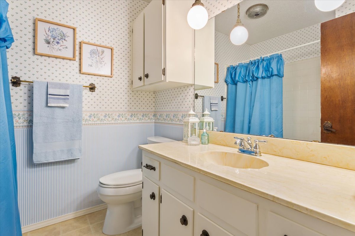 4015 Ramada Trail Georgetown, TX 78628 - Photo 26 of 35 Full bath with a wainscoted wall, vanity, curtained shower, wallpapered walls, and light tile patterned flooring