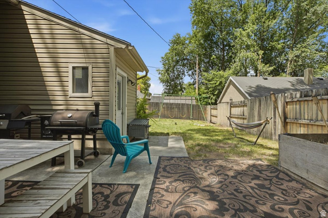 565 East 800 North Logan, UT 84321 - Photo 19 of 27 Expansive backyard featuring a concrete patio, mature trees, a wooden privacy fence, and a storage shed