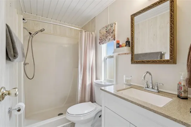 a bathroom with a granite countertop sink a toilet and shower