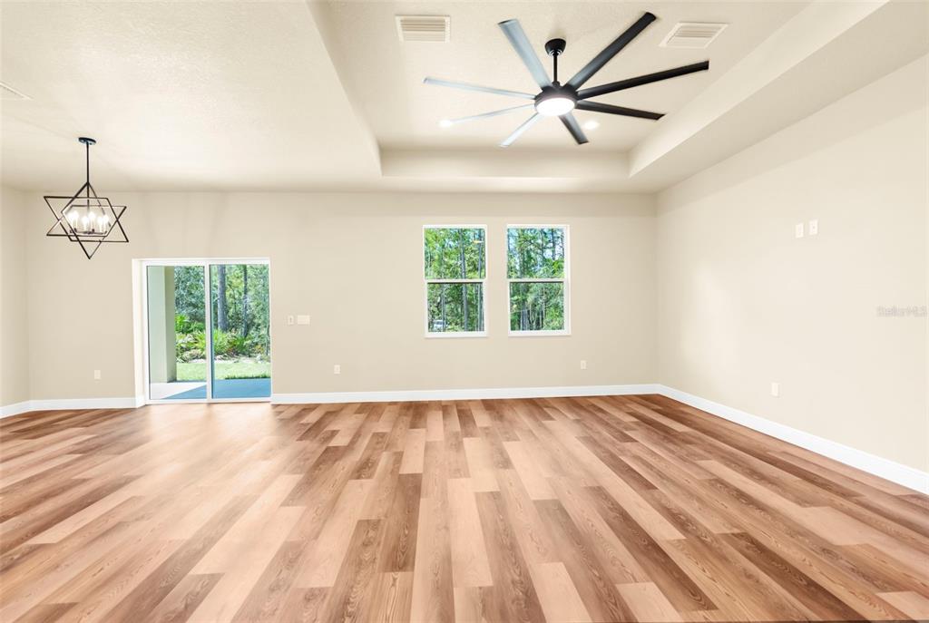 16143 Penn State Road Weeki Wachee, FL 34614 - Photo 4 of 45 an empty room with wooden floor ceiling fan and windows