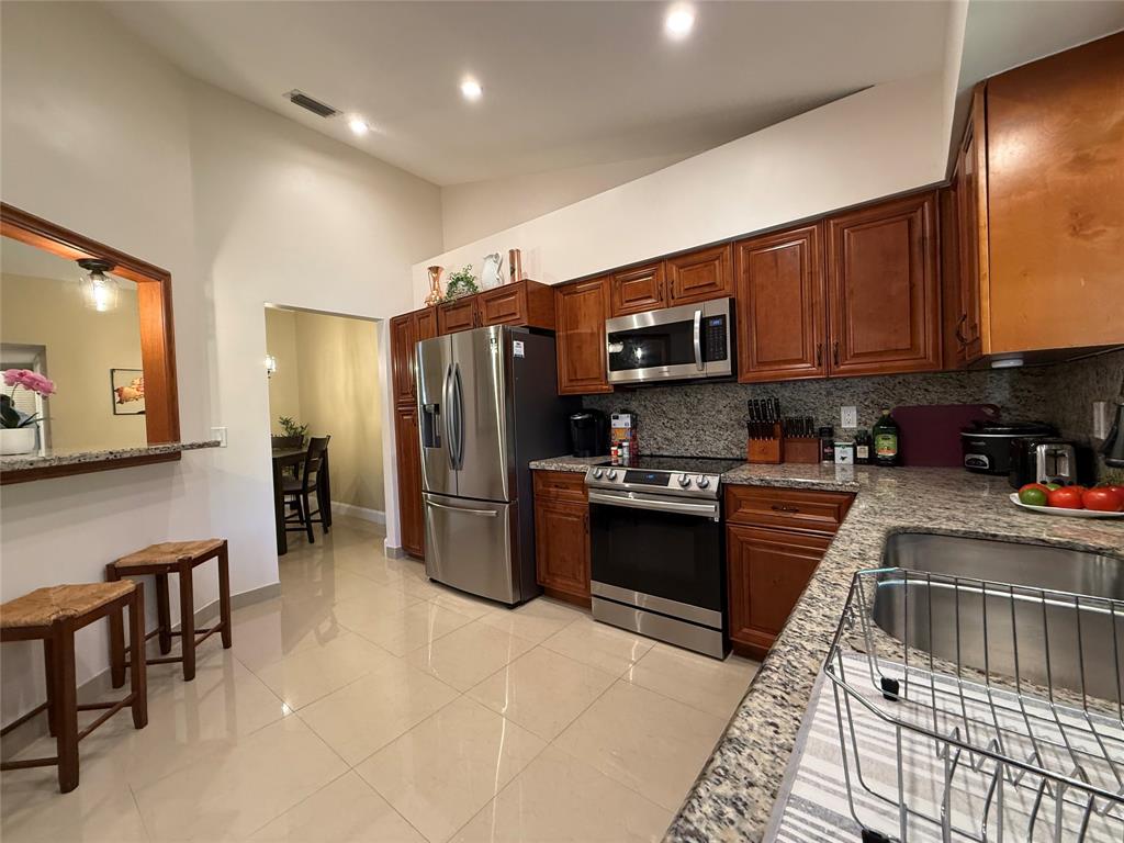 9237 Northwest 9th Place, Unit 9237 Plantation, FL 33324 - Photo 11 of 44 a kitchen with stainless steel appliances granite countertop a refrigerator stove top oven a sink and dishwasher