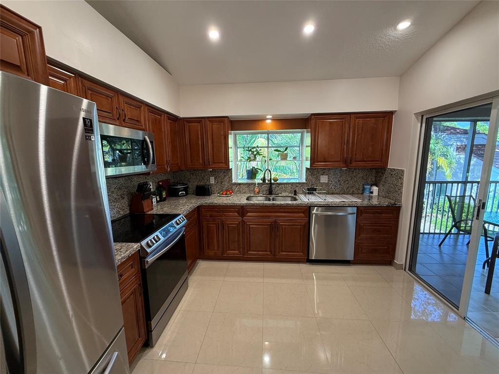 9237 Northwest 9th Place, Unit 9237 Plantation, FL 33324 - Photo 13 of 44 a kitchen with stainless steel appliances granite countertop a refrigerator a sink a stove a washer dryer and a refrigerator