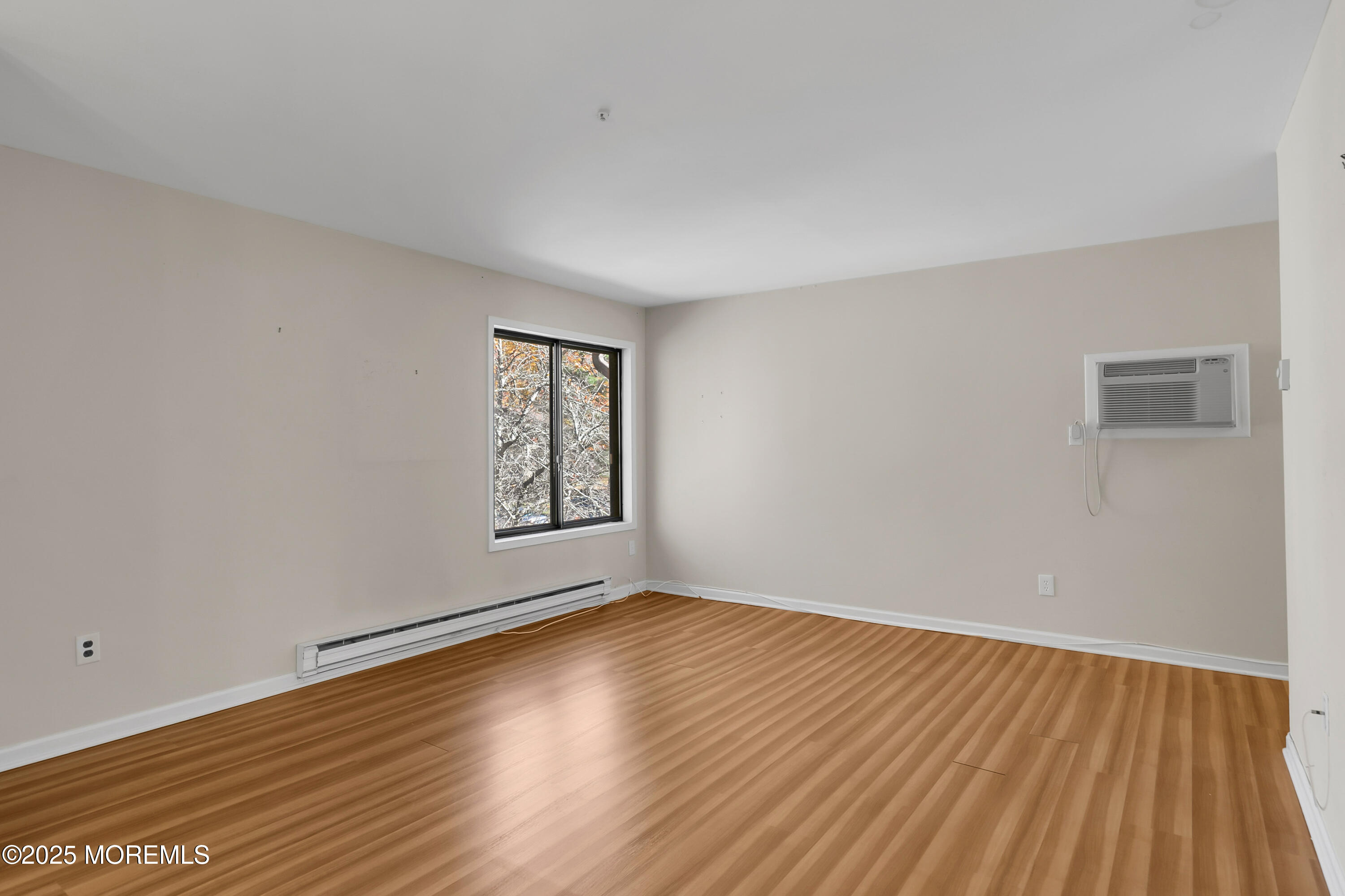 26 Meadow Green Circle, Unit K Manalapan, NJ 07726 - Photo 6 of 27 a view of an empty room with wooden floor and a window