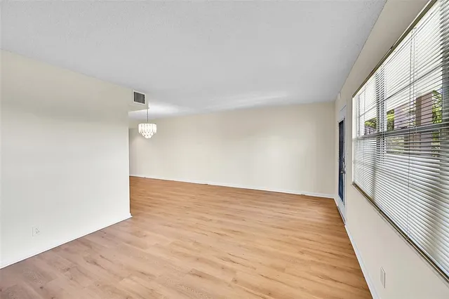 a view of a room with wooden floor kitchen chandelier and windows