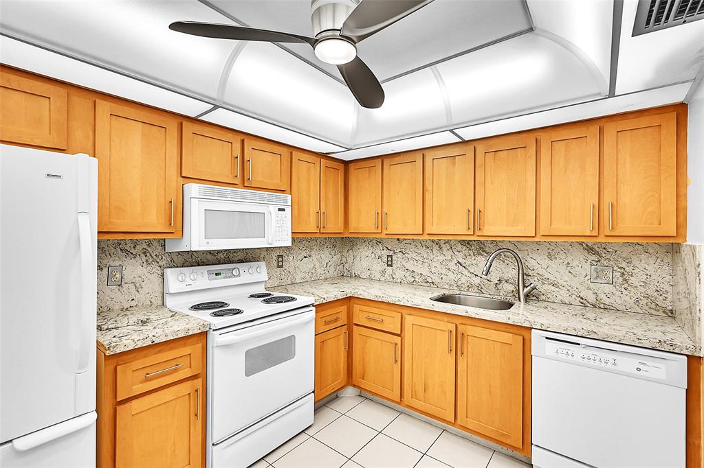 1902 Bermuda Circle, Unit H3 Coconut Creek, FL 33066 - Photo 5 of 25 a kitchen with stainless steel appliances granite countertop a sink a stove and cabinets