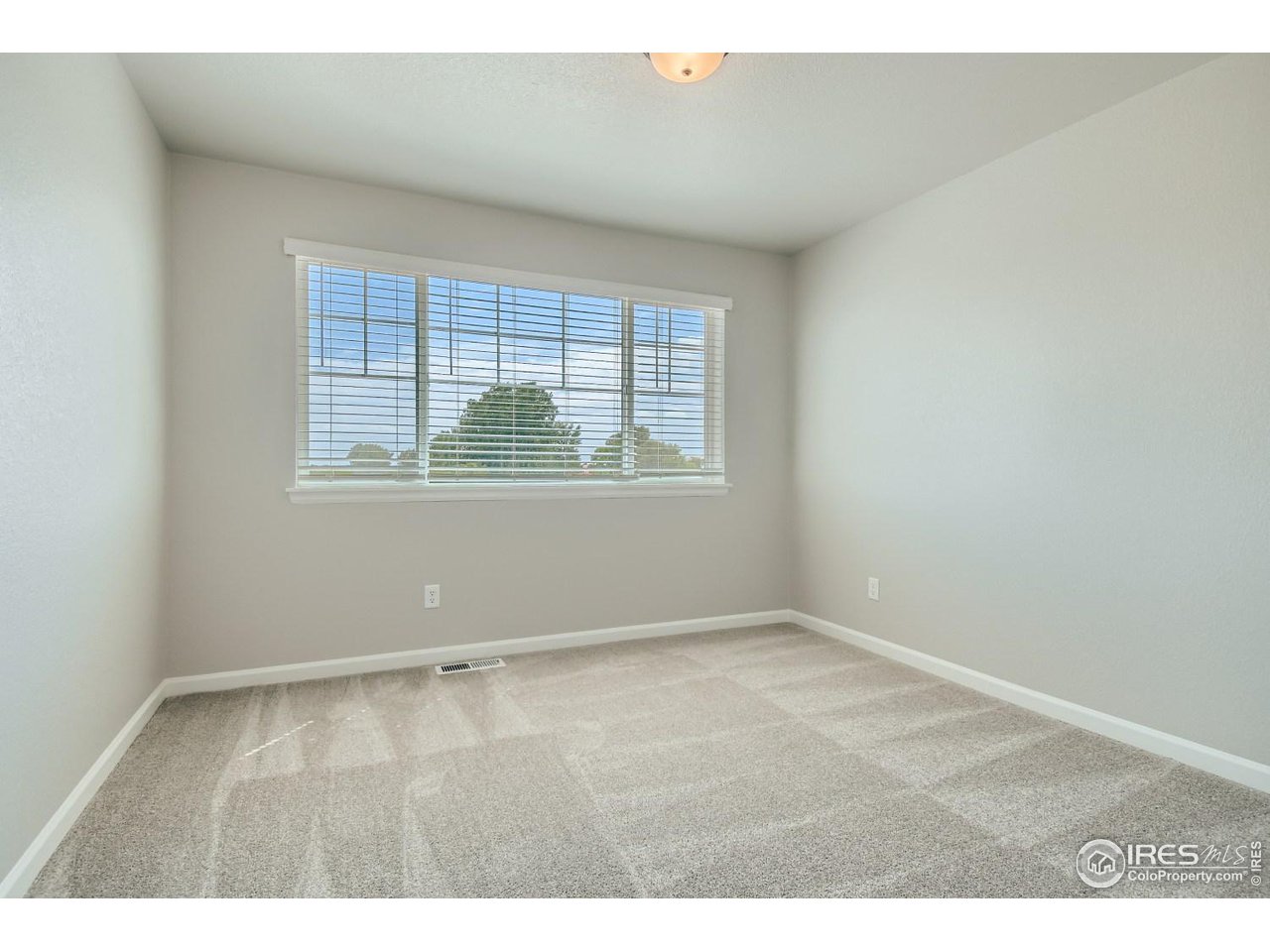 2540 Brookstone Drive, Unit B Milliken, CO 80543 - Photo 22 of 25 an empty room with wooden floor and windows