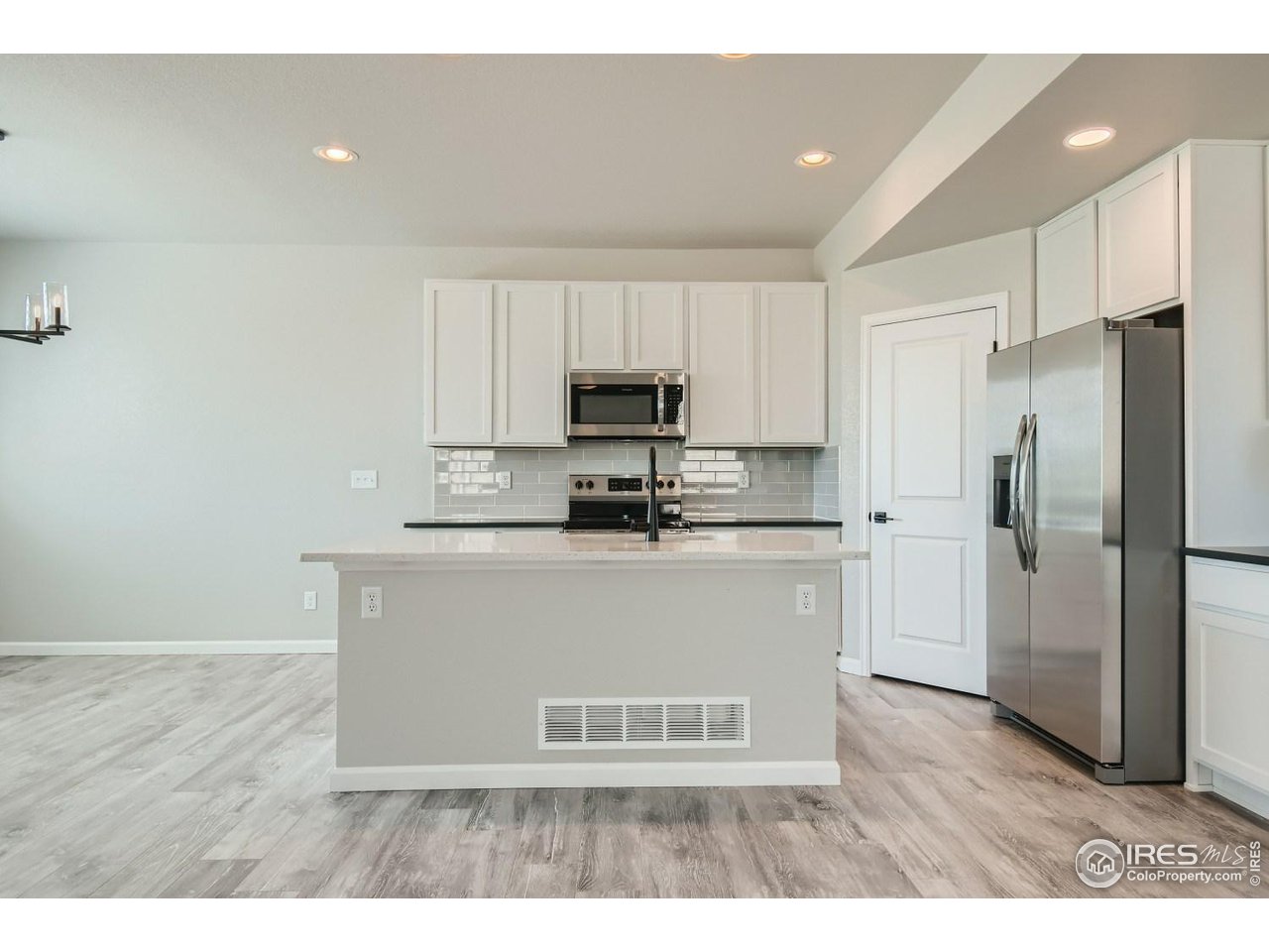 2540 Brookstone Drive, Unit B Milliken, CO 80543 - Photo 10 of 25 a kitchen with kitchen island white cabinets and stainless steel appliances