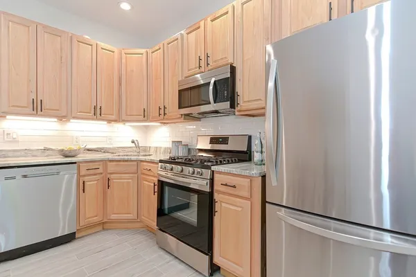 a kitchen with stainless steel appliances granite countertop white cabinets a stove top oven a sink and dishwasher