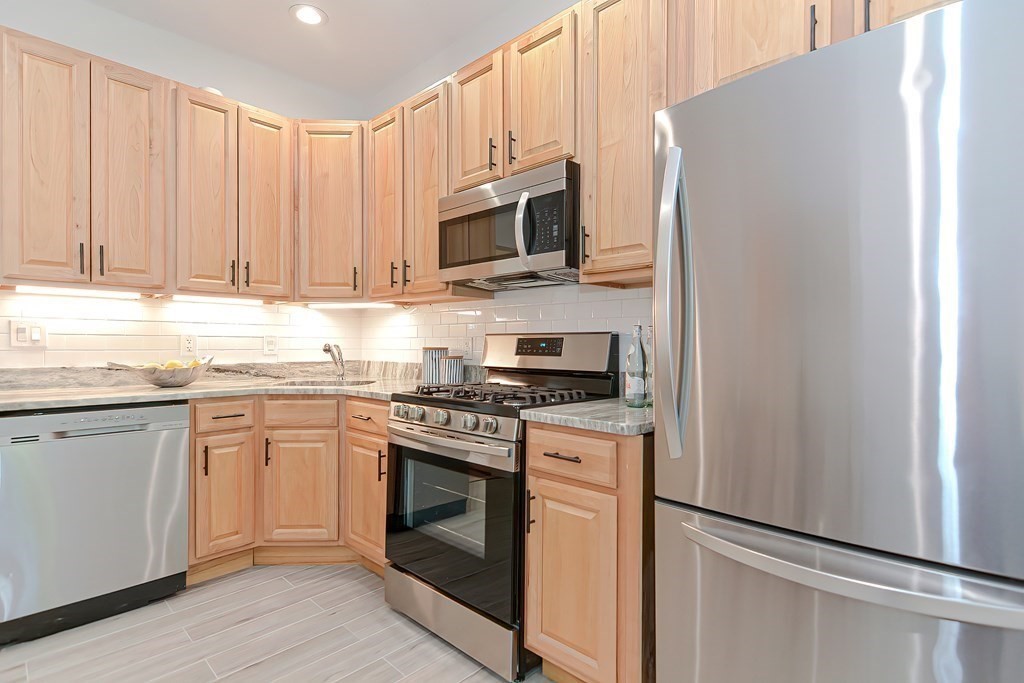 28 Inman Street, Unit 2 Cambridge, MA 02139 - Photo 6 of 24 a kitchen with stainless steel appliances granite countertop white cabinets a stove top oven a sink and dishwasher