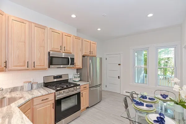 a kitchen with stainless steel appliances granite countertop a stove a sink a microwave a refrigerator and cabinets