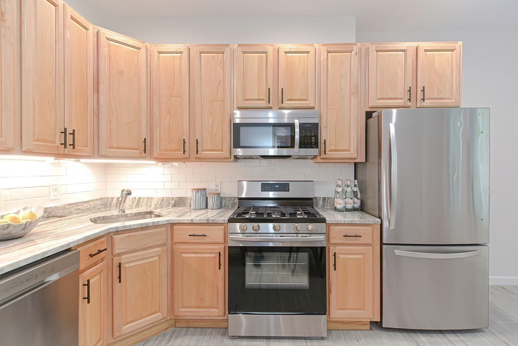 28 Inman Street, Unit 2 Cambridge, MA 02139 - Photo 8 of 24 a kitchen with cabinets stainless steel appliances and a window