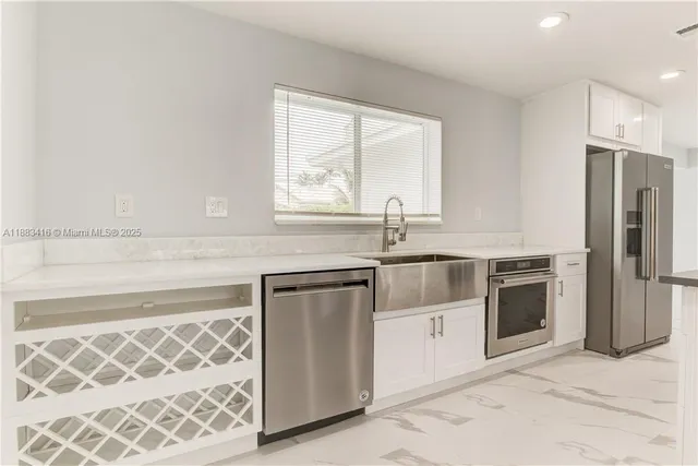 a kitchen with white cabinets and stainless steel appliances