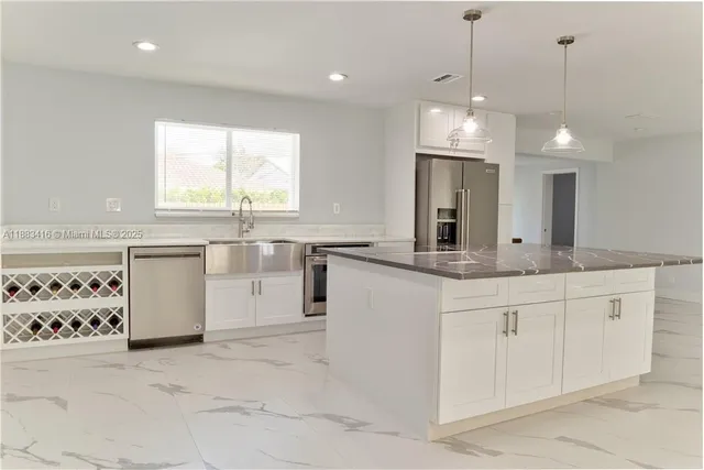 a large white kitchen with a large window a sink and cabinets