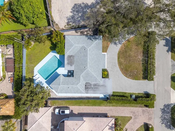 an aerial view of a house with swimming pool and large trees