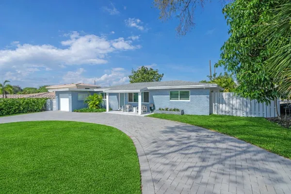 a front view of a house with a yard and potted plants