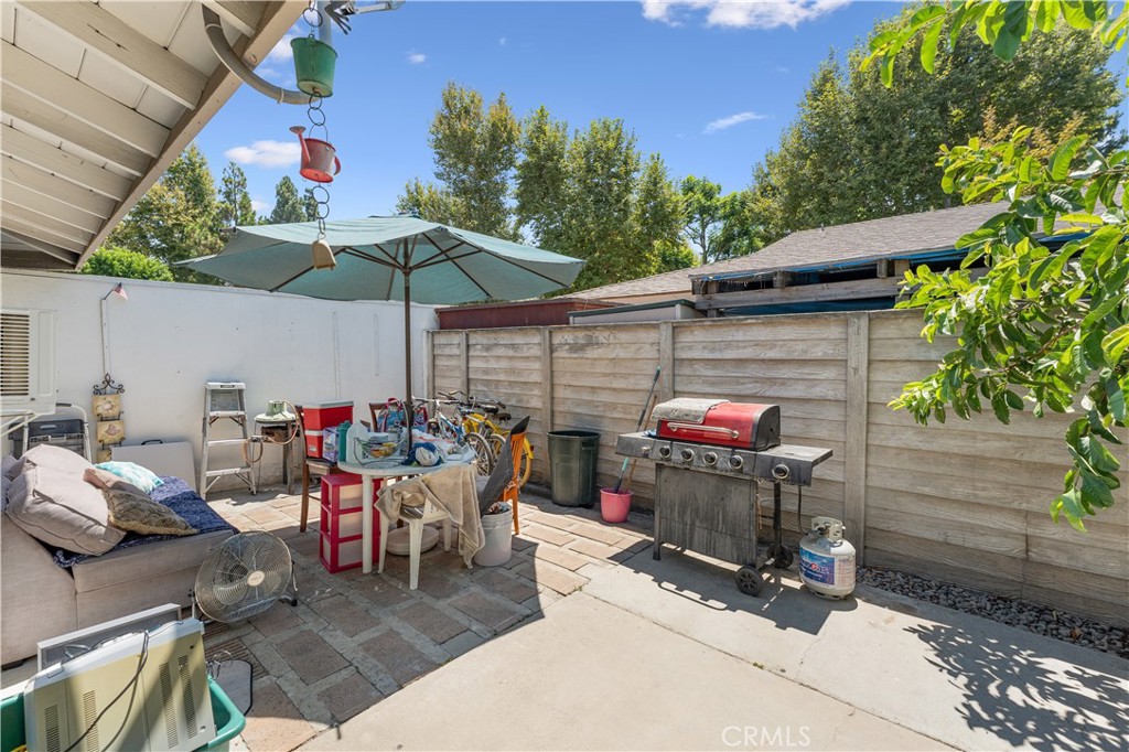 14802 Newport Avenue, Unit 18A Tustin, CA 92780 - Photo 20 of 27 a view of a patio with table and chairs under an umbrella with a barbeque