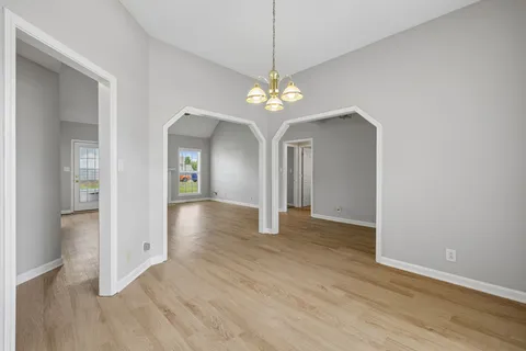 an empty room with wooden floor fan and window