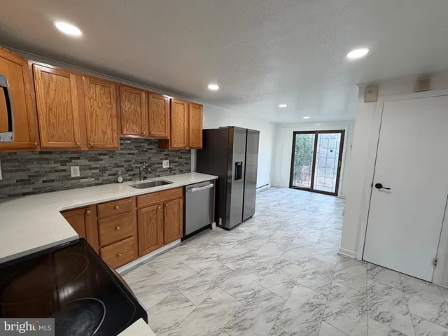 a kitchen with stainless steel appliances granite countertop a stove a sink dishwasher and a refrigerator with wooden cabinets