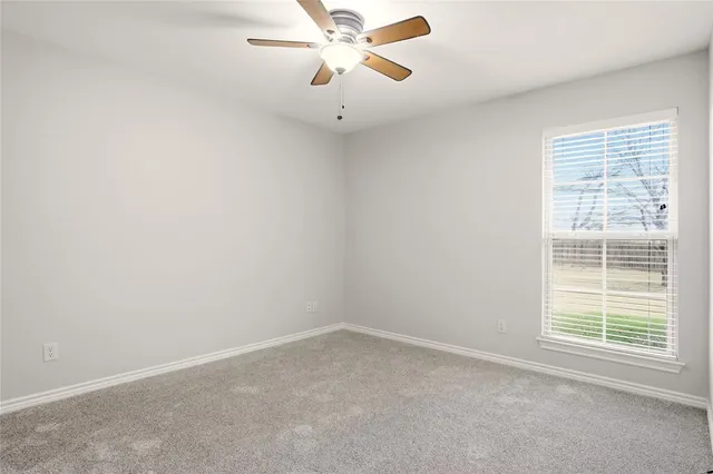 an empty room with a window and a fan