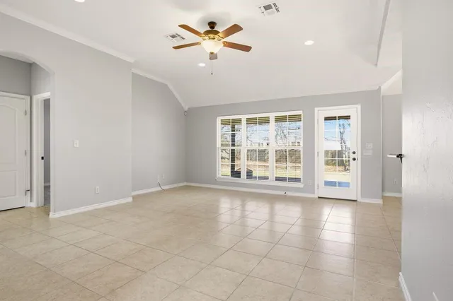 a view of an empty room with a window and a kitchen
