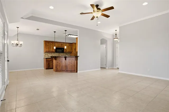 an empty room with chandelier fan and windows