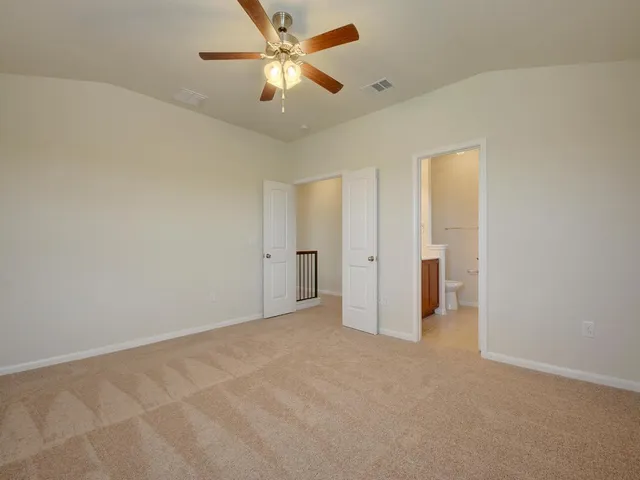 an empty room with closet and a ceiling fan