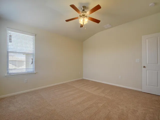 an empty room with a window and a fan