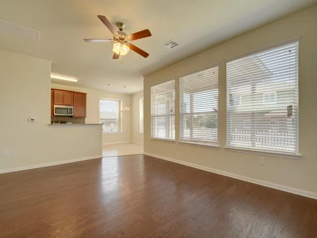 a view of an empty room with a window and wooden floor